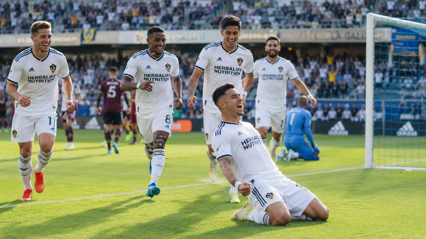 A LA Galaxy soccer player celebrates a goal by sliding on his knees surrounded by happy teammates.